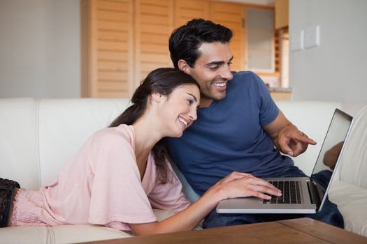 Lovely young couple using a laptop in their living room