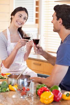 Portrait of a couple having a glass of red wine while cooking in their kitchen