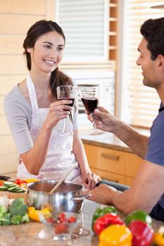 Portrait of a young couple having a glass of wine while cooking in their kitchen