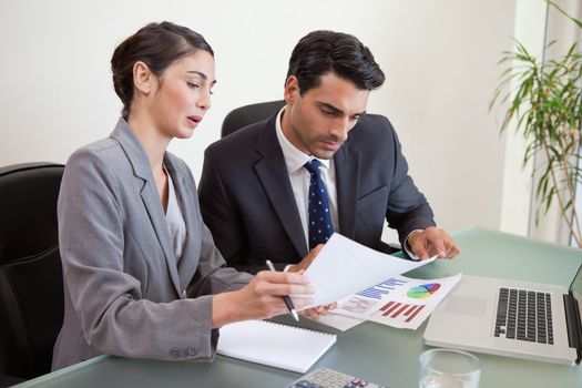 Sales persons working with a notebook in an office