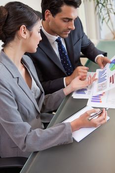 Portrait of sales persons studying graphs in a meeting room