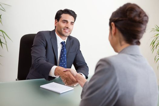 Smiling manager interviewing a female applicant in his office