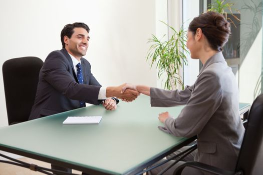 Smiling manager interviewing a good looking applicant in his office