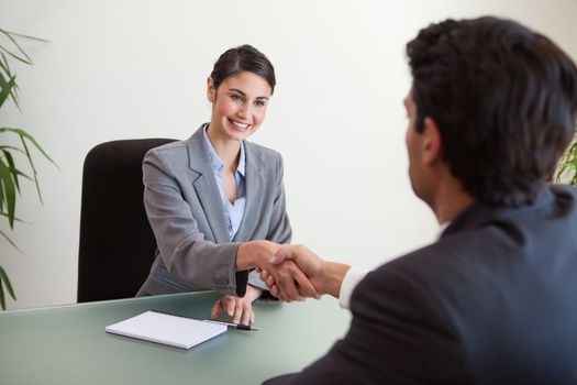 Manager shaking the hand of a customer in her office