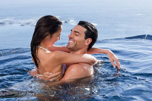 Delighted couple cuddling each other in a swimming pool