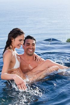 Portrait of a man holding his wife in a swimming pool