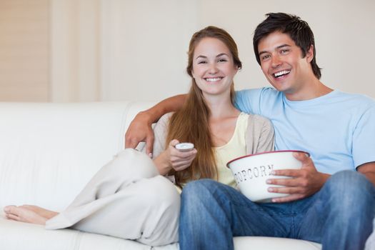 Couple watching television while eating popcorn in their living room
