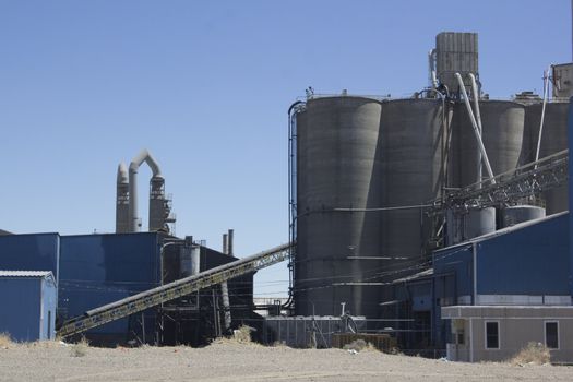 A cement plant with silos and blue skies.