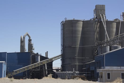 A cement plant with silos and blue skies.