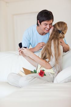 Portrait of a man offering a jewel to his girlfriend in their living room