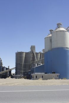 A cement plant with silos and blue skies.