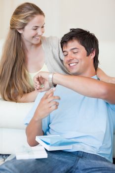 Portrait of a woman offering a watch to her fiance in their living room