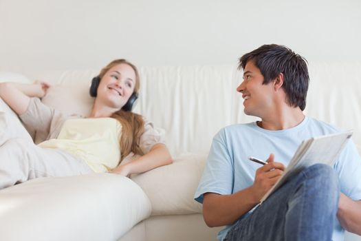 Man doing crosswords while his girlfriend is listening to music in their living room