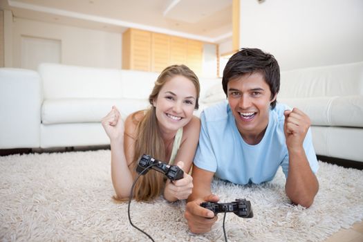 Cheerful young couple playing video games in their living room