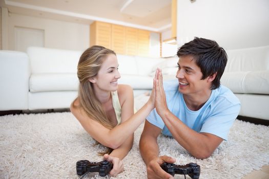 Playful cute couple playing video games in their living room