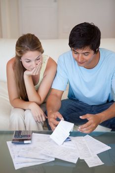 Portrait of a sad couple looking at their bills in their living room
