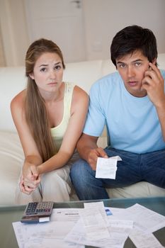 Portrait of a worried couple looking at their receipts in their living room