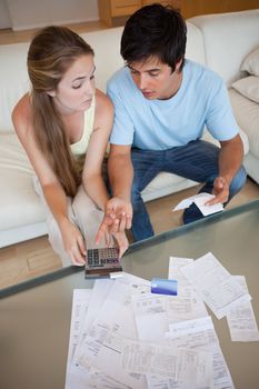 Portrait of a sad couple looking at their receipts in their living room