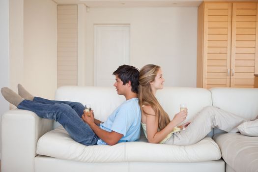Couple sitting back to back with a glass of wine in their living room