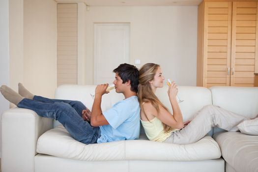 Couple sitting back to back while drinking wine in their living room