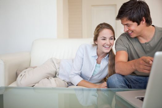 Laughing couple using a notebook in their living room