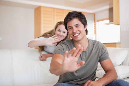 Couple waving at the camera in their living room