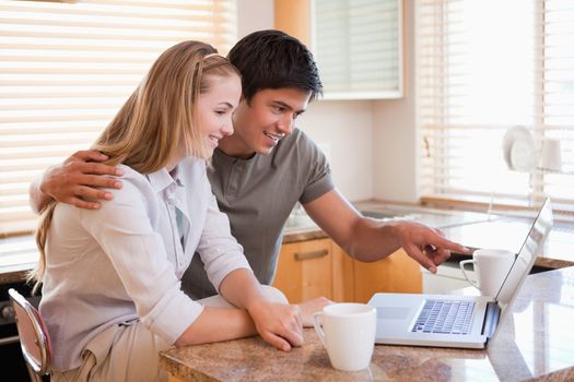 Couple having coffee while using a laptop in their kitchen