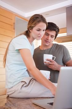 Portrait of a couple having coffee while using a laptop in their kitchen