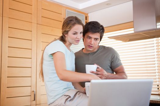 Couple having coffee while using a notebook in their kitchen