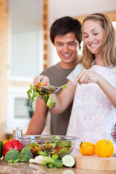 Portrait of a young couple making a salad in their kitchen