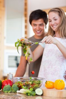Portrait of a charming couple making a salad in their kitchen