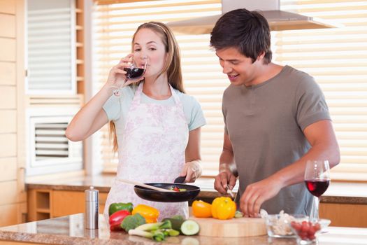 Couple cooking dinner while drinking wine in their kitchen