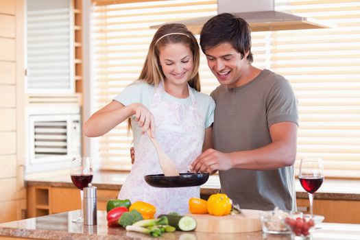 Couple cooking dinner while drinking red wine in their kitchen