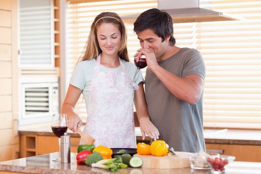 Young couple cooking dinner while drinking red wine in their kitchen
