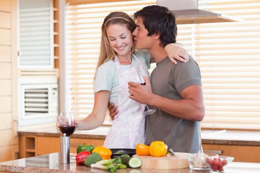 Lovely couple drinking wine while kissing in their kitchen