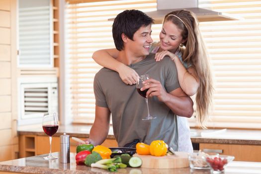 Lovely couple drinking wine while hugging in their kitchen