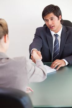 Portrait of a manager shaking the hand of a customer in his office