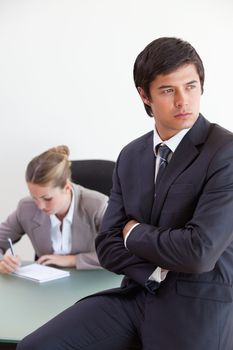 Portrait of a manager posing while his colleague is working in an office