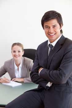 Portrait of a businessman posing while his colleague is working in an office