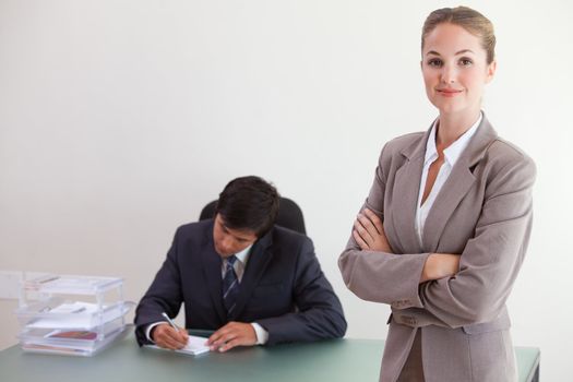 Young busineswosman posing while her colleague is working in an office