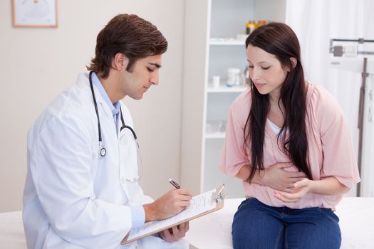 Young male doctor writing down patients symptoms