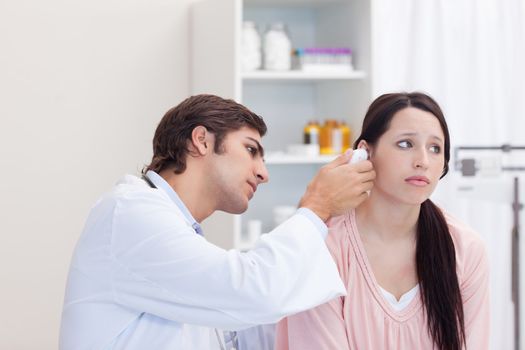 Male doctor examining his female patients ear
