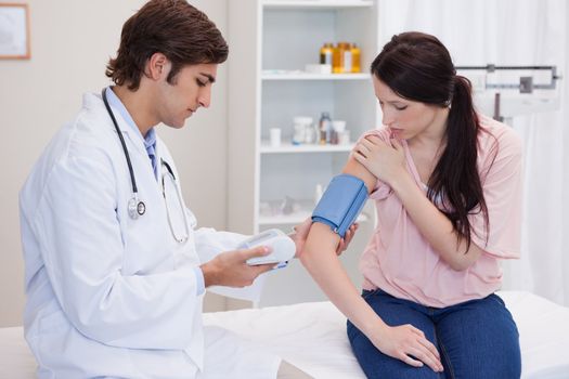 Young doctor taking patients blood pressure
