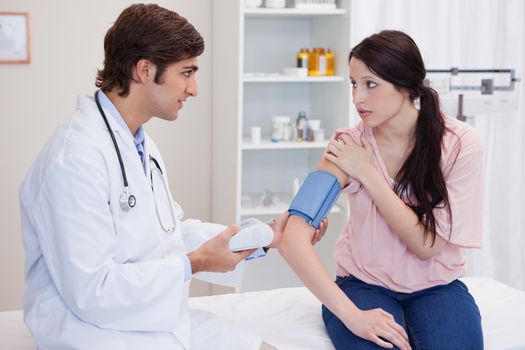 Young doctor checking patients blood pressure