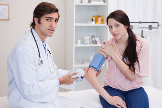 Doctor taking young female patients blood pressure