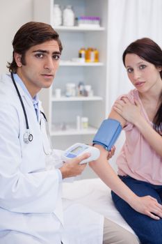 Male doctor examining patients blood pressure