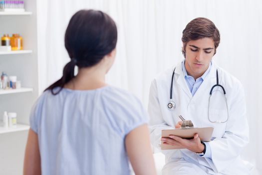 Young physician talking notes while patient is talking