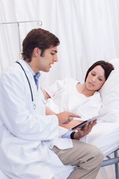 Young doctor showing his patient whats on his tablet
