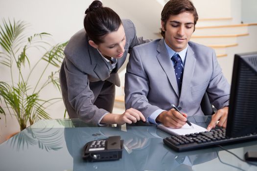 Young businessman taking notes while getting mentored by colleague