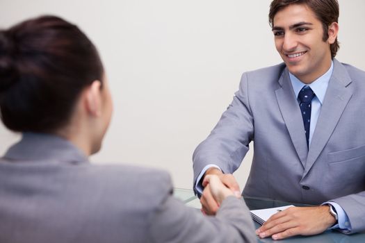 Young business partners sitting at a table shaking hands